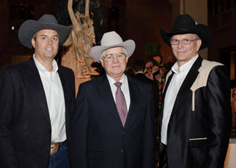 Three men in suits and cowboy hats standing side by side smiling