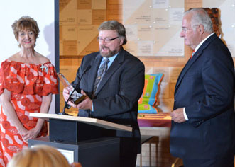Two people presenting award to one recipient