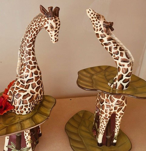 Two tables incorporating painted sculptures of giraffes.
