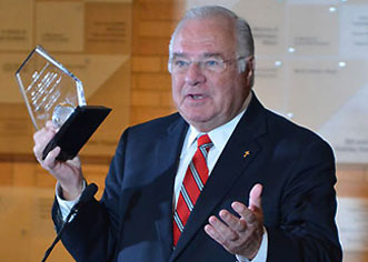 J. Joe Ricketts giving a speak holding his glass award