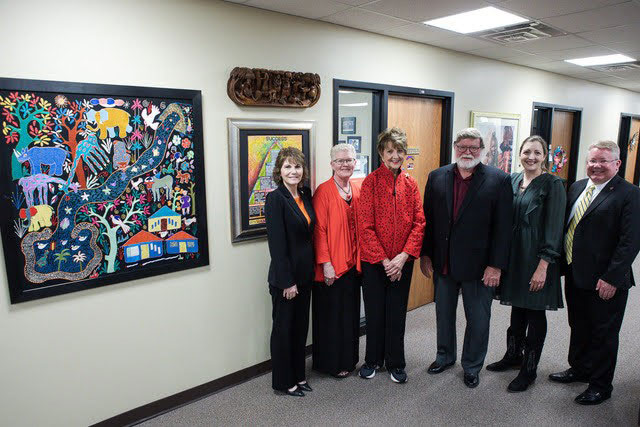 Dr. Doug Christensen, Natalie Hahn and four more people posing next to a piece of African wall art.