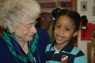Senior woman holding young African girl in elementary school