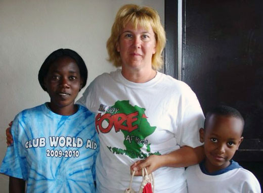American teacher with her arms around two African students, smiling