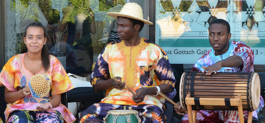 Three African musicians playing instruments along a street