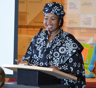 African woman wearing traditional robe of dark blue and shite flower pattern giving a speach