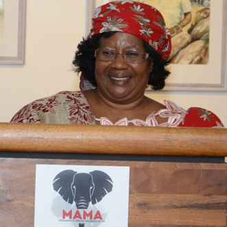 African women speaking at a podiem with the MAMA elephant logo on front of podium