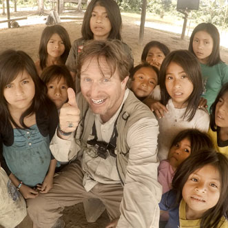 Dean Jacobs smiling with a thumbs-up with children in the Amazon rain forest
