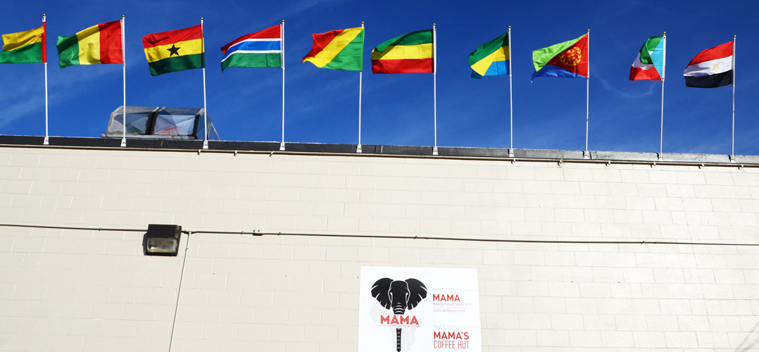 Flags of ten different countries flying on top of a building with blue skies