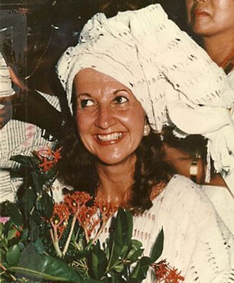Natalie Hahn wearing white traditional head wrap with bouquet of flowers in her hands