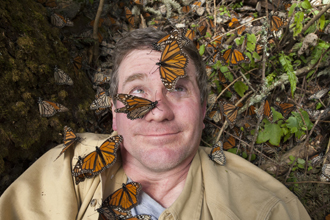 Joel Sartore with Monarch butterflies landing all over his face