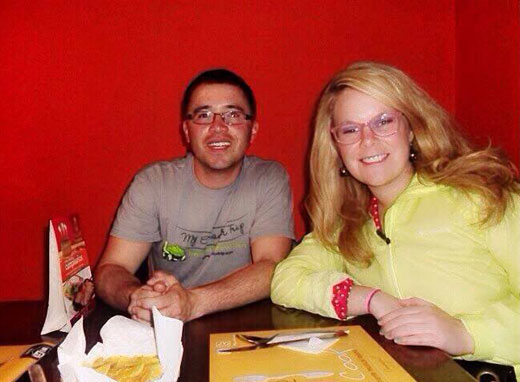 Two teachers at a restaurant table in front of a bright red wall
