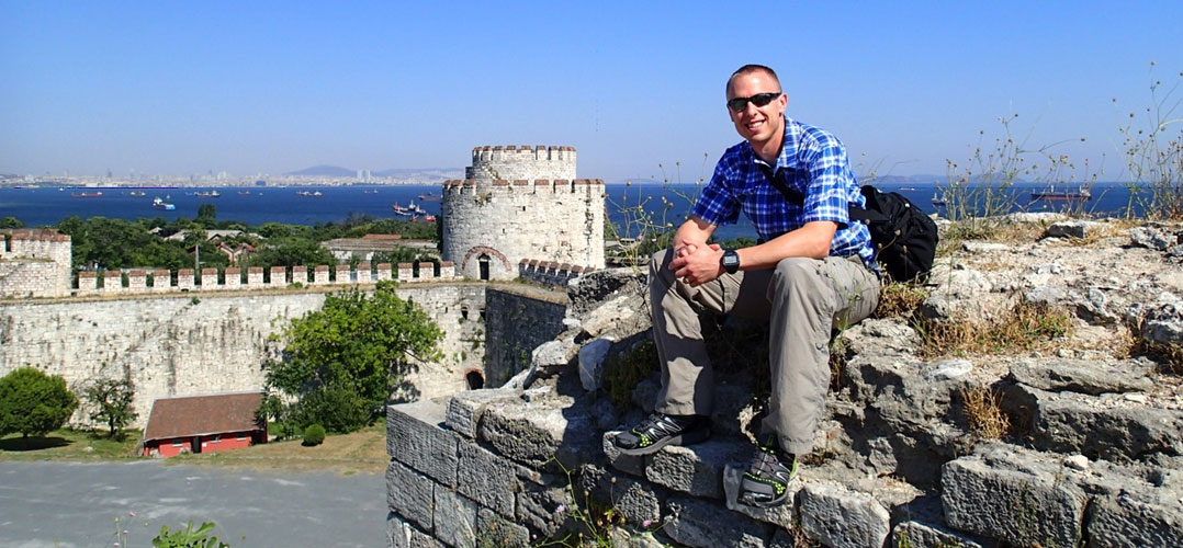 Teacher, Kevin Witte, sitting atop a stone wall in Turkey